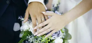 Nahaufnahme eines Brautpaars, das sich die Hände reicht – Fokus auf den frisch angesteckten Eheringen