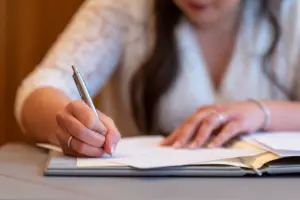 Braut unterschreibt standesamtliche Dokumente bei der Hochzeit