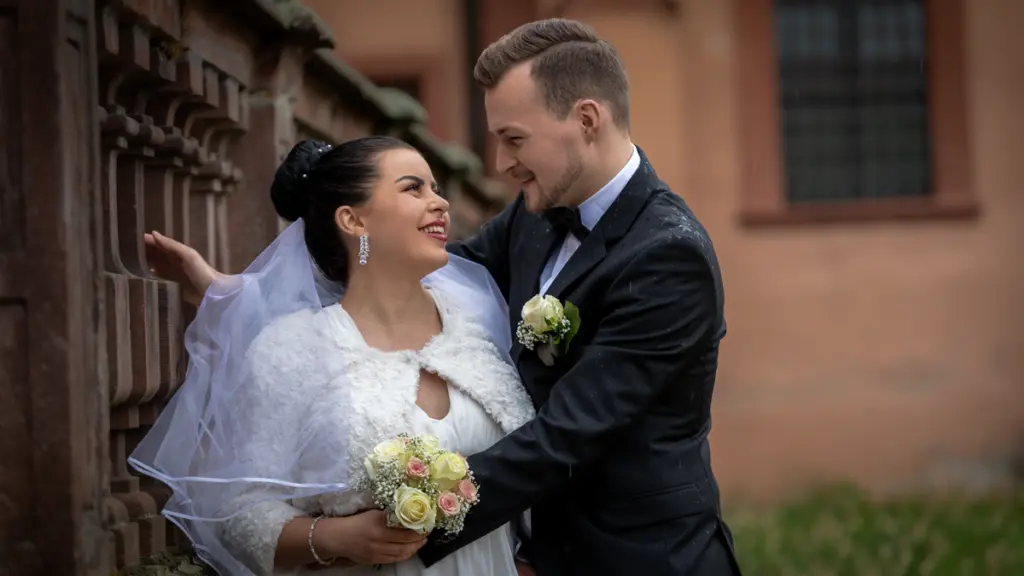 Brautpaar umarmt sich vor historischem Gebäude in der Pfalz.